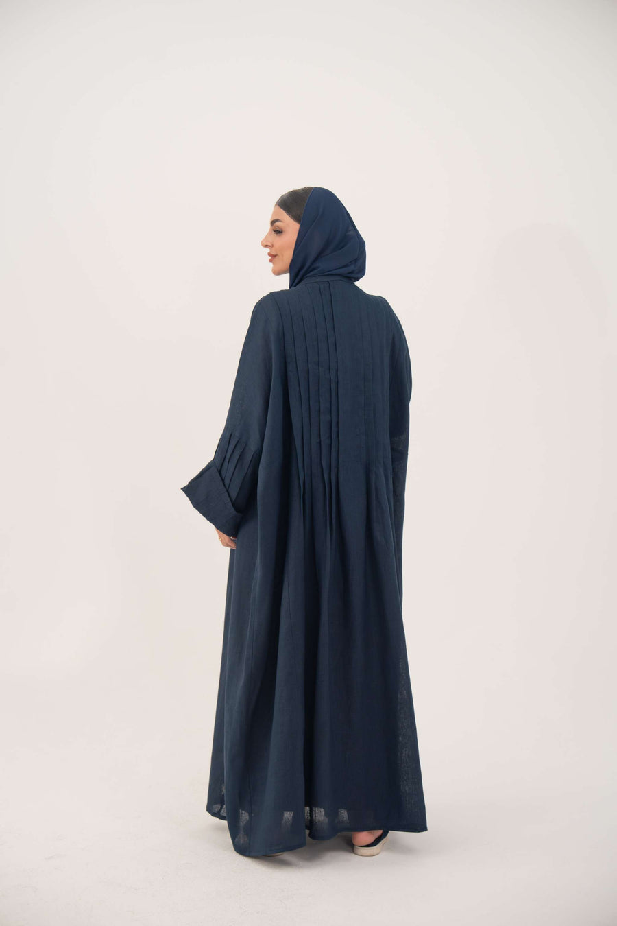 Woman wearing full-length open-front abaya navy blue linen with vertical stitched pleats