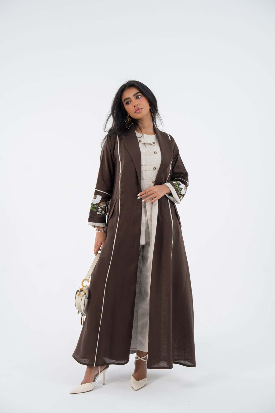 woman wearing floral drift linen abaya in warm brown with white floral embroidery and flowing blazer-style cut