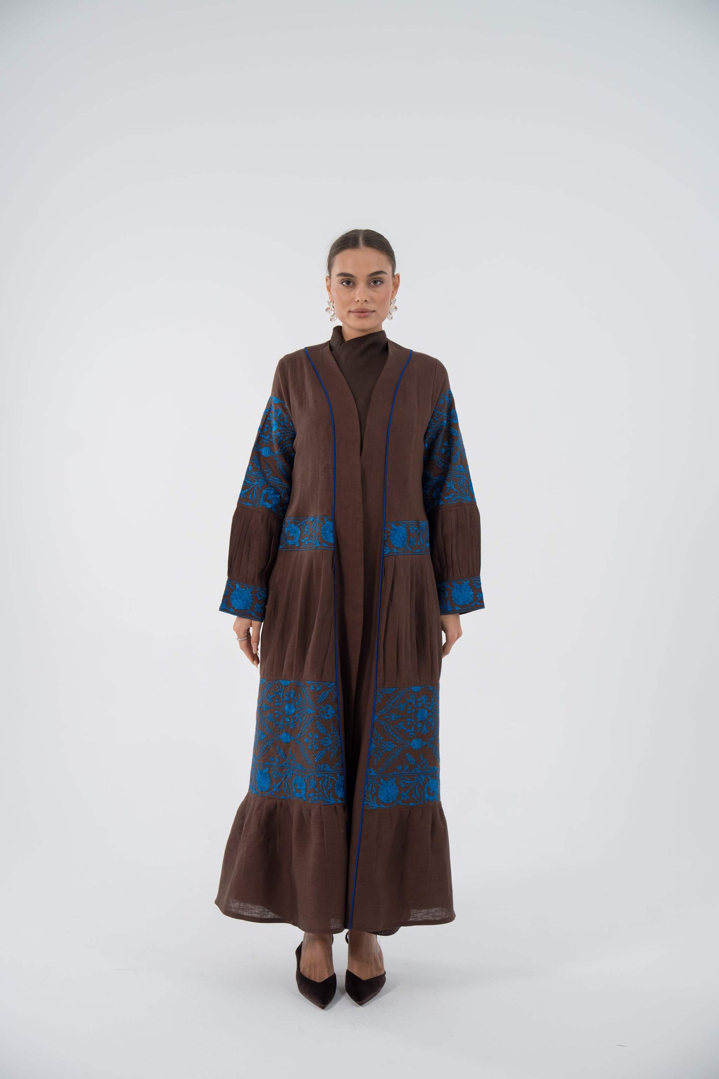 woman wearing blue bloom linen abaya with blue floral embroidery and flowing ruffle hem