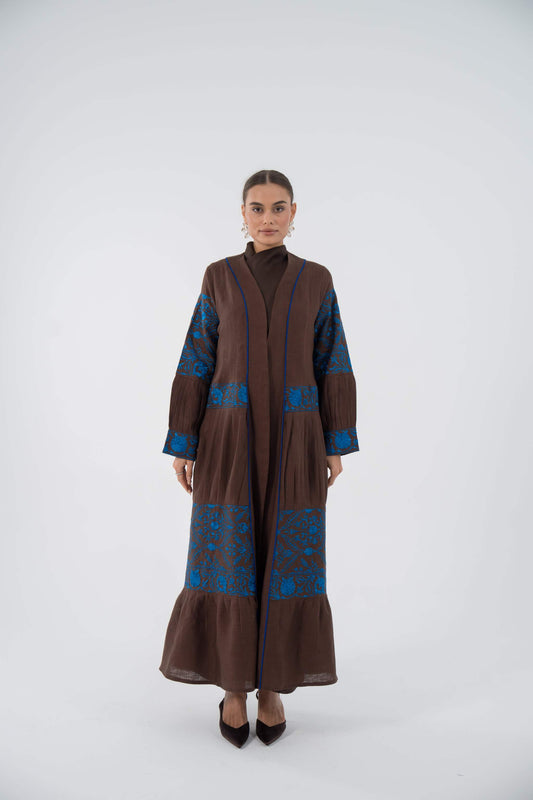 woman wearing blue bloom linen abaya with blue floral embroidery and flowing ruffle hem