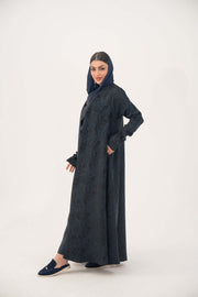 Woman wearing elegant navy jacquard abaya with subtle textured pattern and soft shimmer, standing against white background