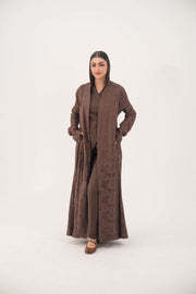 Woman wearing full-length relaxed A-line jacquard silk abaya in warm cocoa brown with subtle woven floral pattern and long sleeves