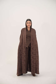 Woman wearing a full-length jacquard silk abaya with subtle floral pattern in warm cocoa brown color.