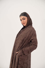 Woman wearing warm cocoa brown jacquard silk abaya with subtle floral pattern and long sleeves.