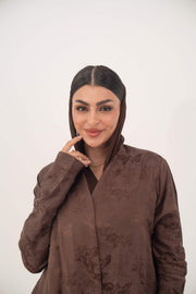 Woman wearing a warm cocoa brown jacquard silk abaya with subtle floral pattern and long sleeves in a relaxed A-line cut.