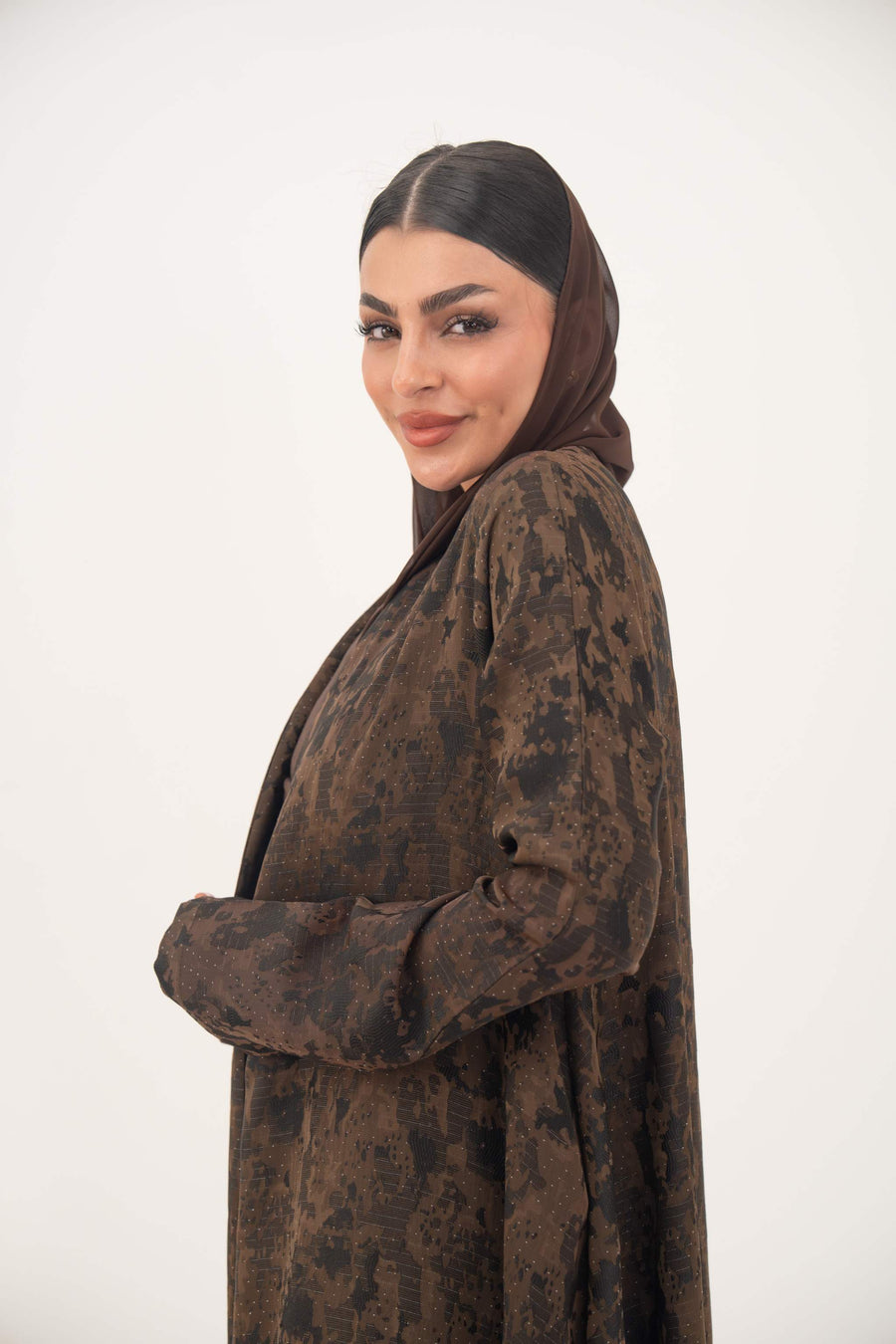 Woman wearing a lightweight jacquard silk abaya in rich espresso brown with subtle tonal pattern and side pockets