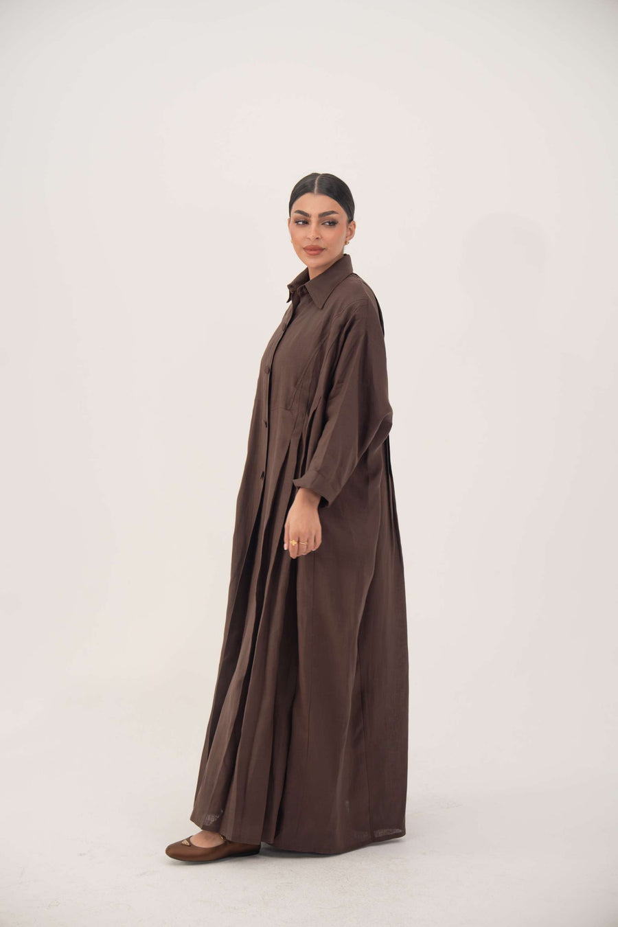 woman wearing deep cocoa brown linen abaya with shirt collar and button-down front in flowy silhouette