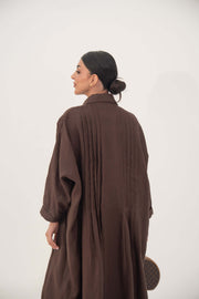 Back view of a woman wearing a deep cocoa brown, flowy linen abaya with a shirt collar and relaxed long sleeves