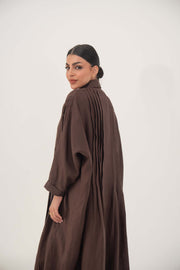 Woman wearing a deep cocoa brown linen shirt-inspired abaya with relaxed long sleeves and a pleated back design
