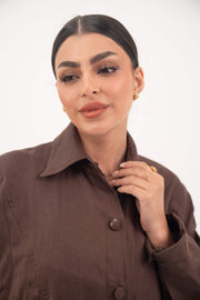 Close-up of a woman wearing a deep cocoa brown linen Jupitor abaya with a classic shirt collar and tonal button-down front.
