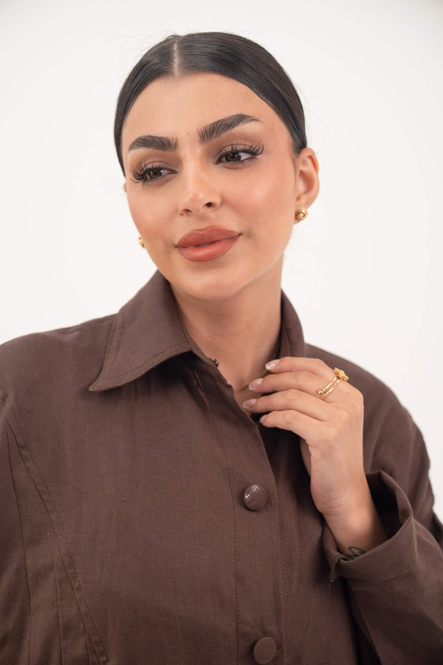 Close-up of a woman wearing a deep cocoa brown linen Jupitor abaya with a classic shirt collar and tonal button-down front.