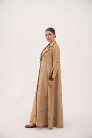 Dark brown linen abaya with beige pleated side panels and cream floral embroidery, featuring a draped lapel and A-line silhouette.