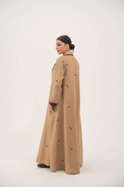 Dark brown linen abaya with beige pleated side panels and cream floral embroidery, A-line silhouette with pleats, draped lapel collar.