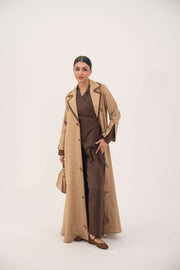 Woman wearing a dark brown linen abaya with beige pleated side panels and cream floral embroidery, featuring a draped lapel and A-line silhouette