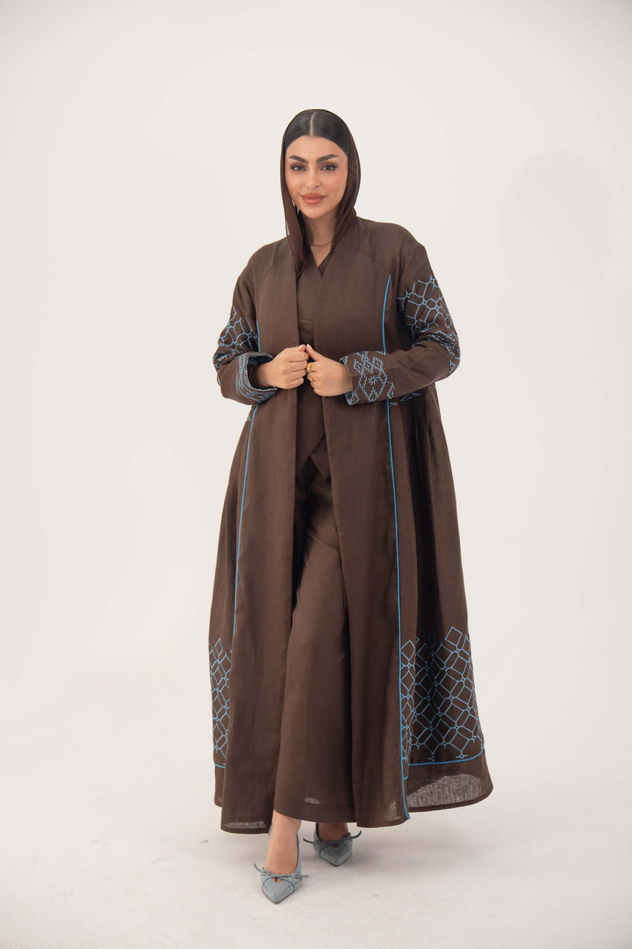 Mocha brown linen-blend abaya with sky-blue embroidery and blue piping, batwing cut, open front, worn with matching pants.
