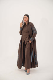 Mocha brown linen-blend abaya with sky-blue embroidery on sleeves and back, batwing cut, blue piping, open front, and light-blue inner cuffs.