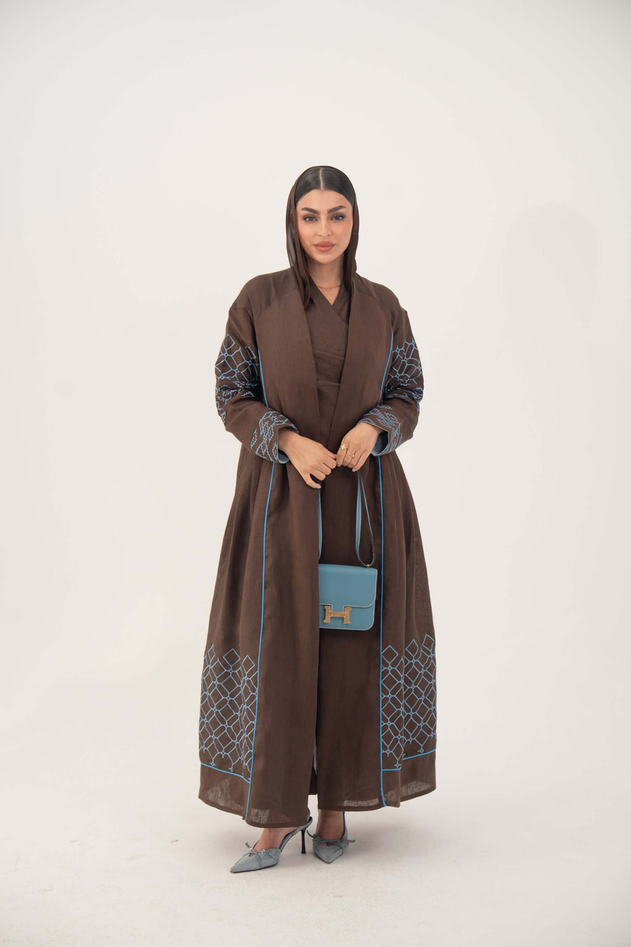 Mocha brown linen-blend abaya with sky-blue embroidery and piping, batwing cut, open front, and light-blue cuff details.