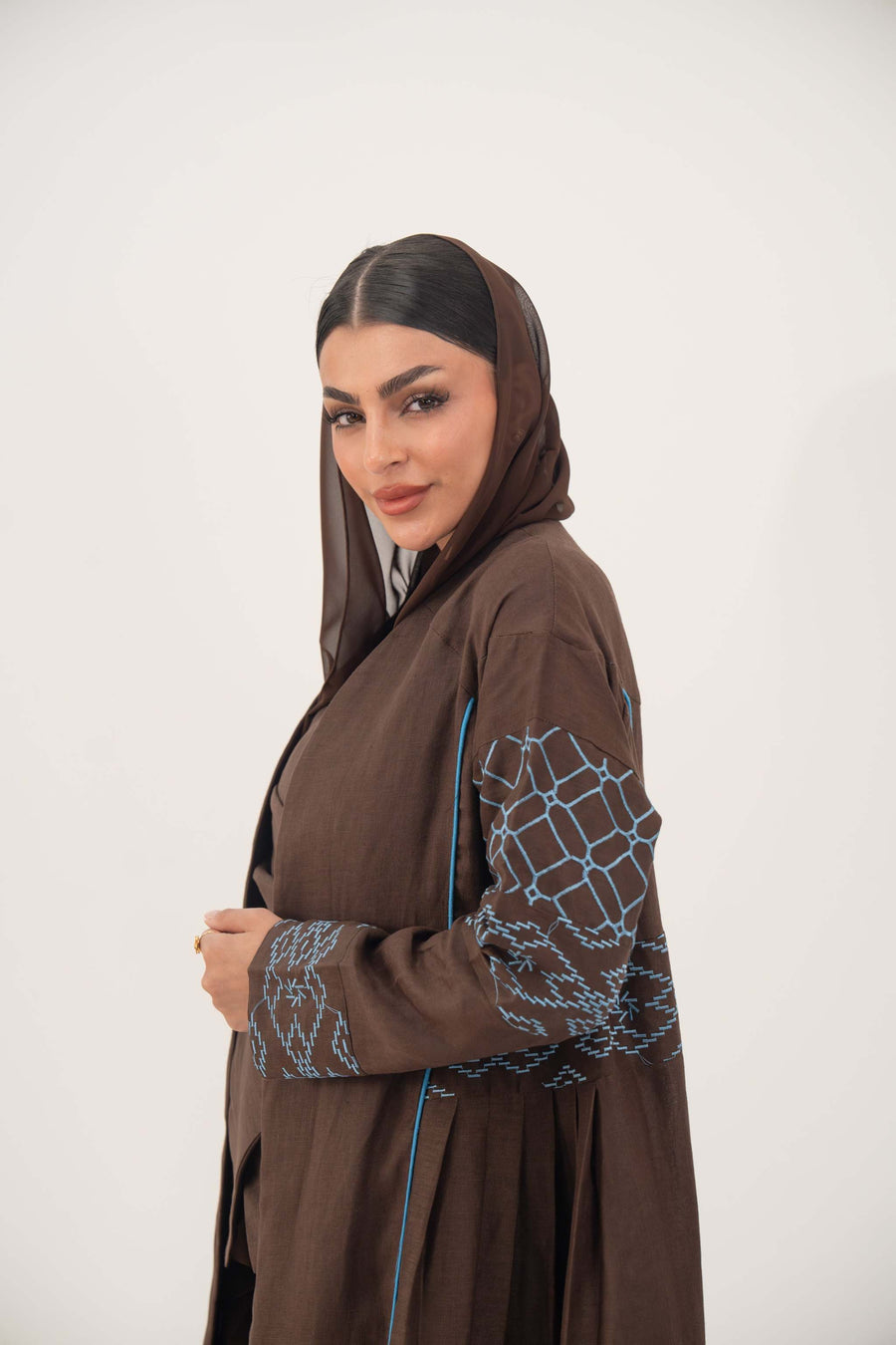 Mocha brown lightweight linen-blend abaya with sky-blue embroidery and batwing sleeves featuring blue piping and light-blue cuff details.