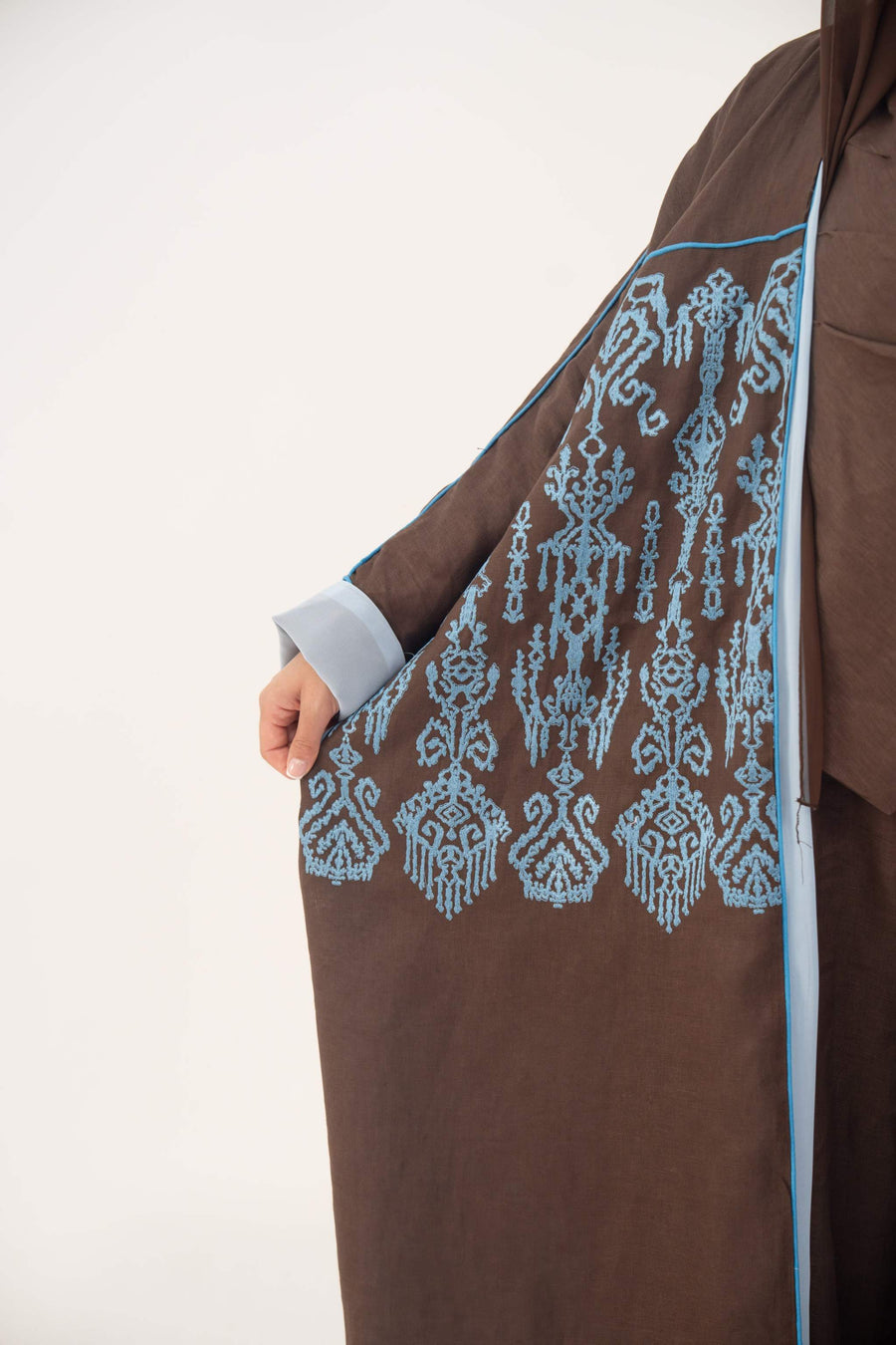 Mocha brown lightweight linen bisht abaya with blue shak embroidery and light blue piping on sleeves and shoulders.