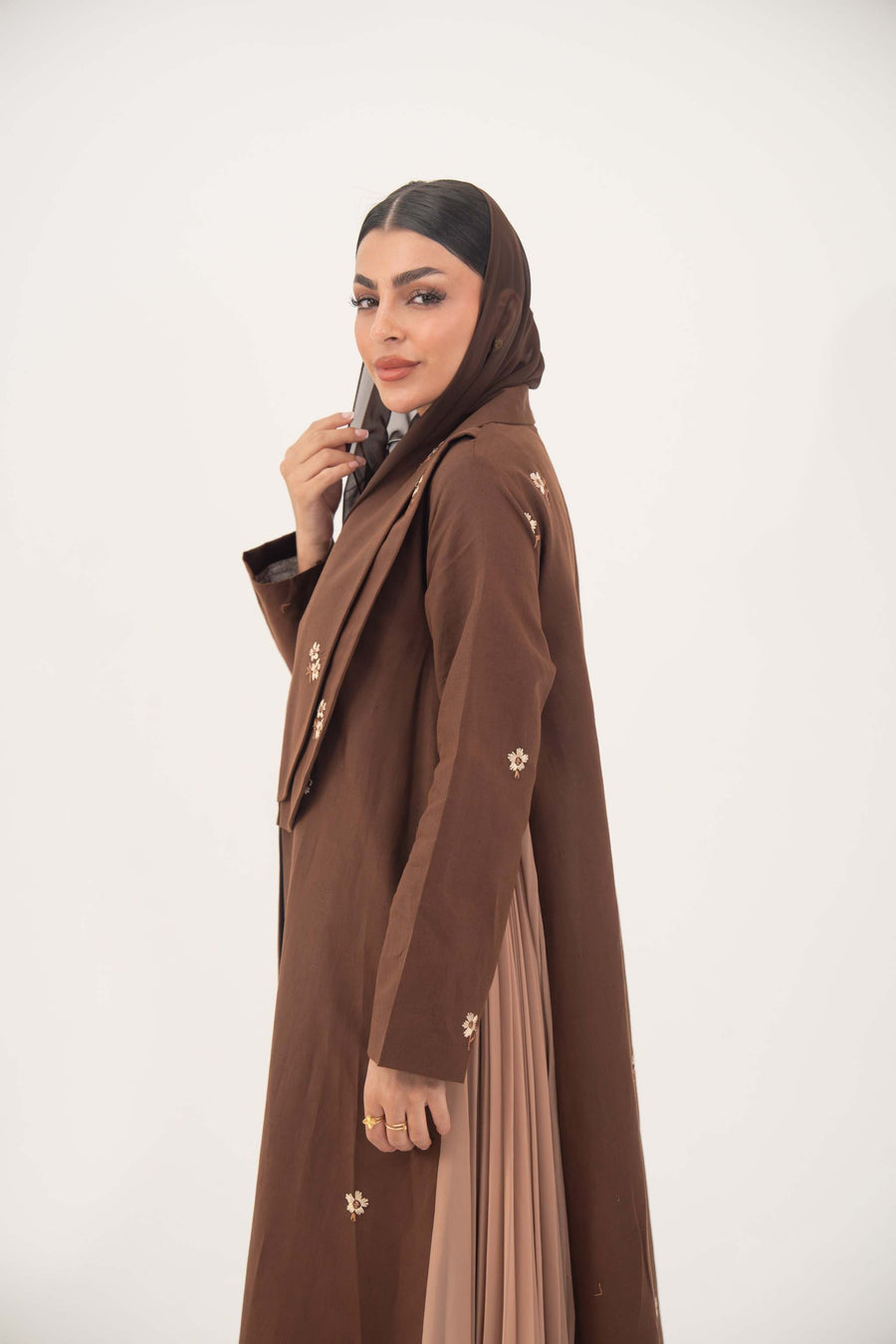 Brown linen blazer abaya with delicate embroidery and pleated chiffon side panels, worn by a woman with a matching brown headscarf.