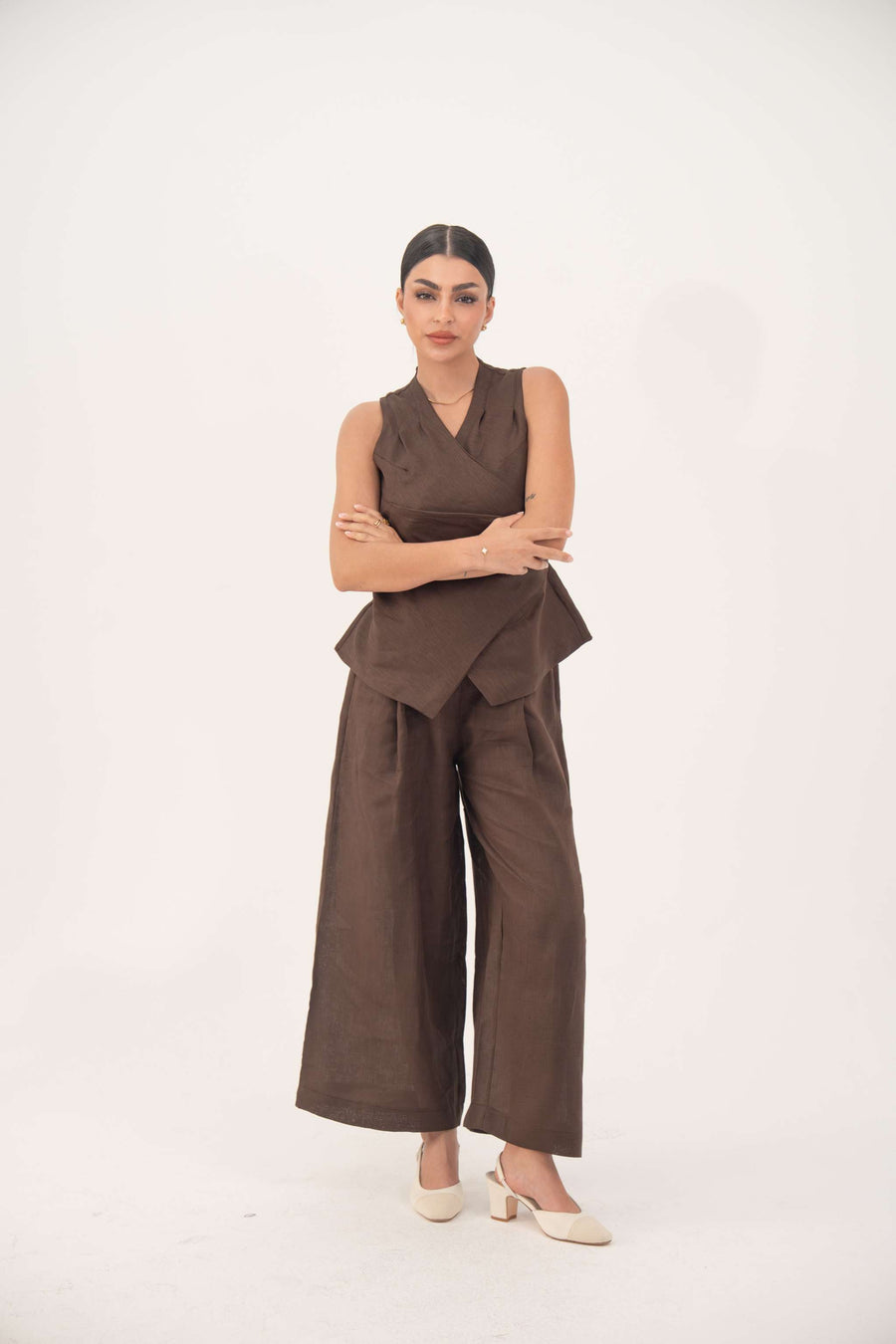 Woman wearing a sleeveless brown linen vest with a modern wrap-style cut and tailored finish paired with matching wide-leg pants-Brown Vest