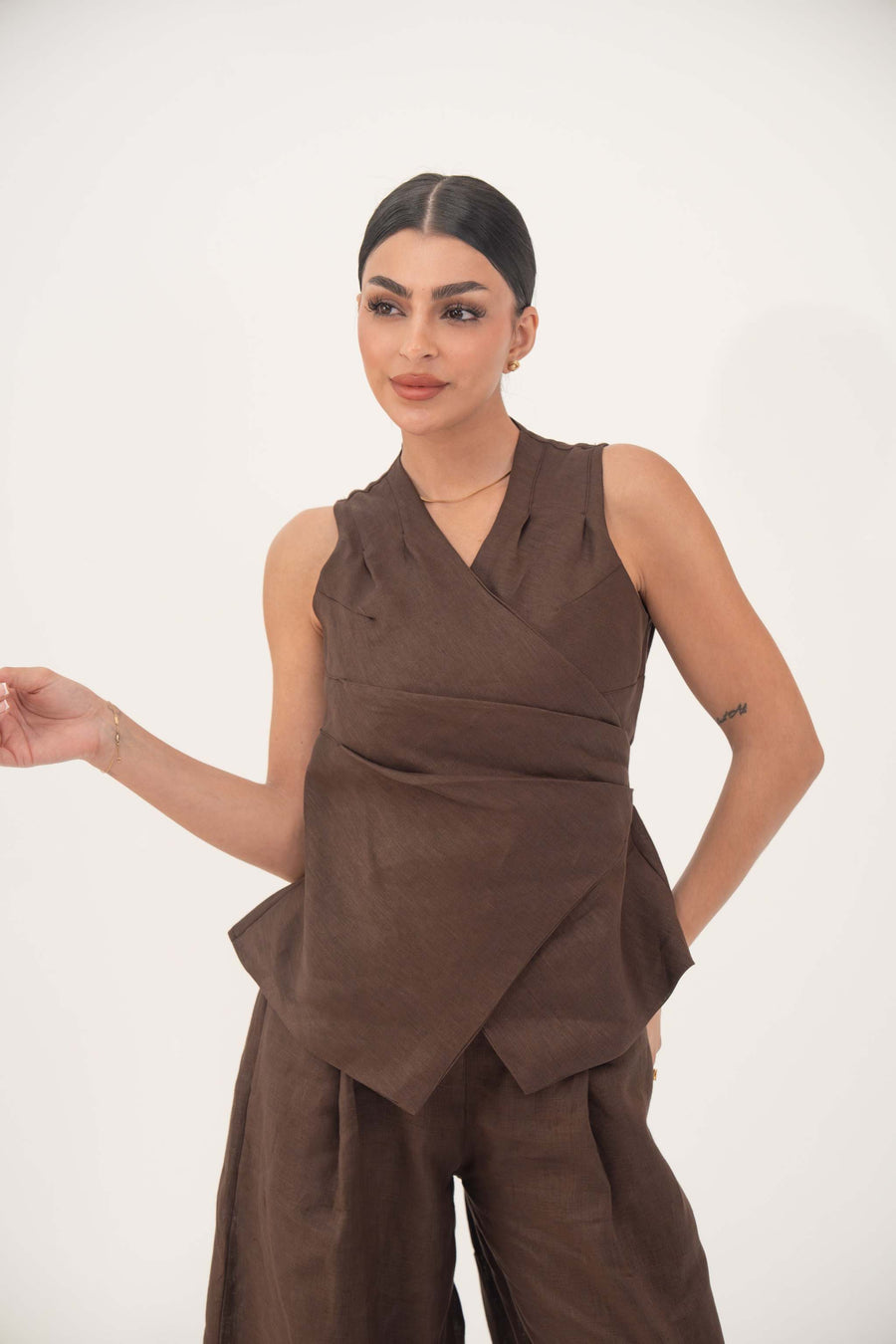 Woman wearing a tailored sleeveless brown vest with a modern wrap-style cut made of breathable linen.