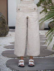 Beige modern pant made of 100% linen with wide-leg silhouette and cropped length, styled with sandals.