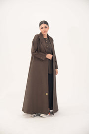 Woman wearing a dark chocolate brown jacquard blazer abaya with sharp lapels, structured tailoring, and faux pockets.