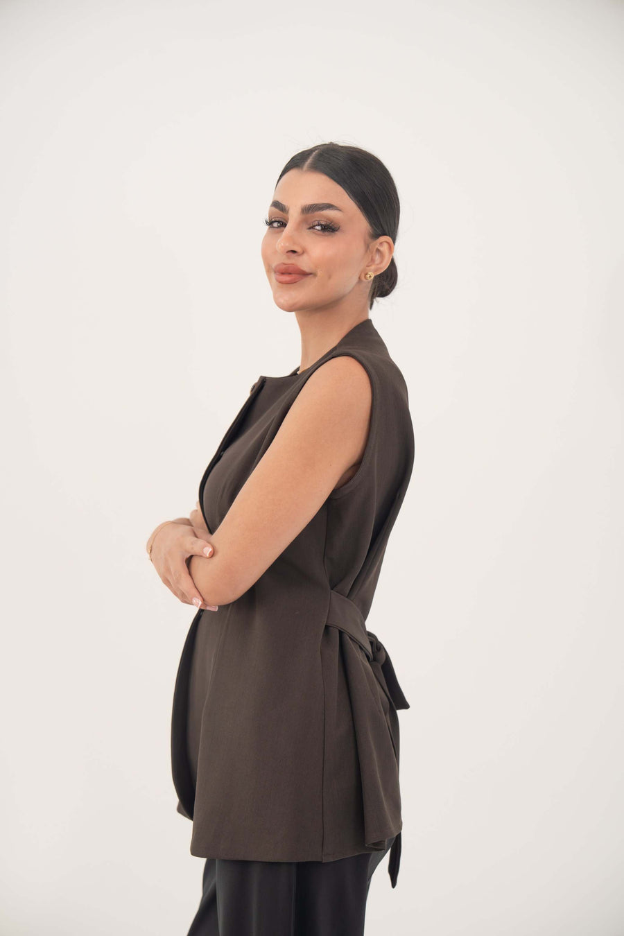 Brown sleeveless crepe vest with nine front buttons and a tailored fit, styled on a model