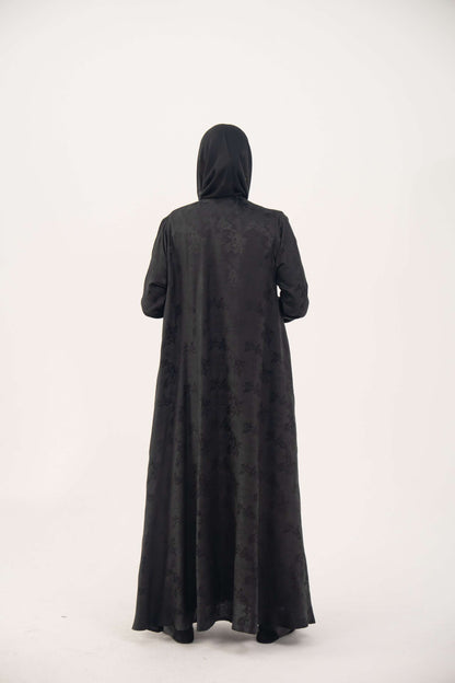 Back view of a black jacquard silk abaya with tone-on-tone floral weave, featuring a fluid A-line cut, relaxed shoulders, open front, straight sleeves, and discreet side pockets.