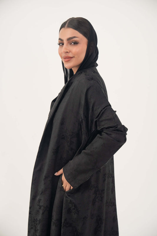 Elegant black jacquard silk Hakaya abaya with tone-on-tone floral weave and relaxed A-line silhouette.