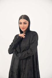 Elegant black jacquard silk abaya with tone-on-tone floral weave, A-line cut, open front, and hidden side pockets.