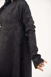 Black jacquard silk abaya with tone-on-tone floral weave, A-line cut, relaxed shoulders, open front, straight sleeves, and discreet side pockets.