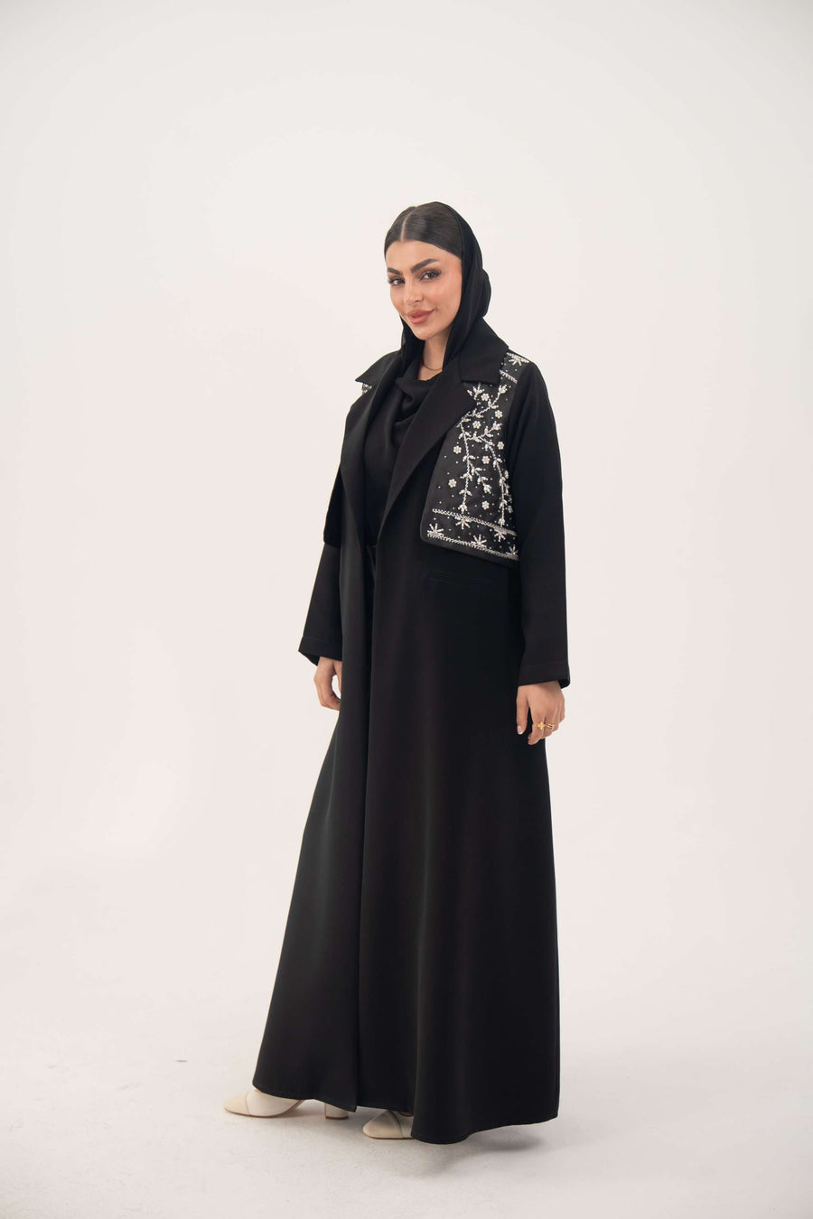 Woman wearing sleek black blazer abaya with embroidered satin vest and flowing crepe fabric