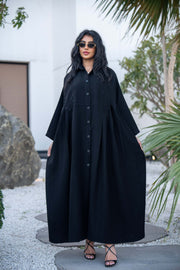 Woman wearing a classic black crepe abaya with a flowing silhouette and button-down front outdoors - Hannah