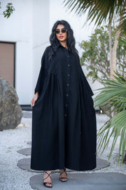 Woman wearing a classic black crepe abaya with a flowing silhouette and button-down front outdoors - Hannah