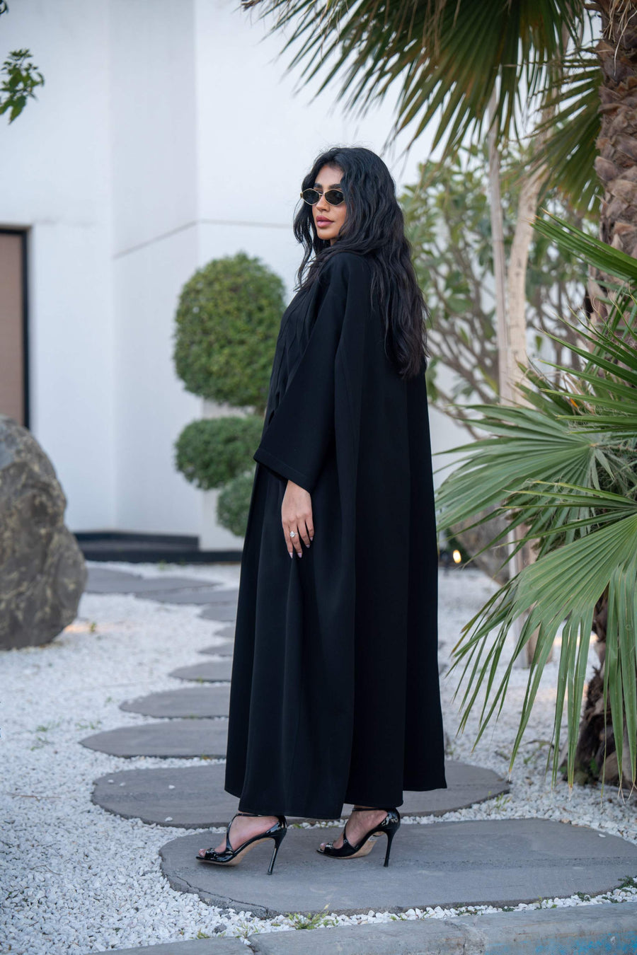 Woman wearing a classic black crepe abaya with a flowing silhouette and button-down front outdoors - Hannah