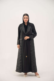 Woman wearing a black jacquard blazer abaya with a textured pattern and classic lapels, featuring a tailored and elegant silhouette.