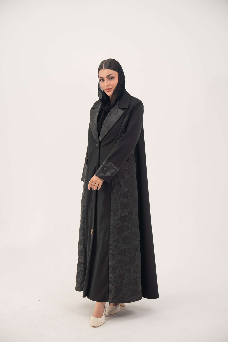 Black jacquard blazer abaya with textured pattern and classic lapels worn by woman for formal occasions