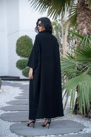 Woman wearing a classic black crepe abaya with a flowing silhouette and button-down front outdoors - Hannah
