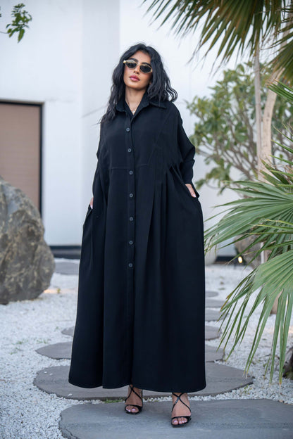 Woman wearing a classic black crepe abaya with a flowing silhouette and button-down front outdoors
