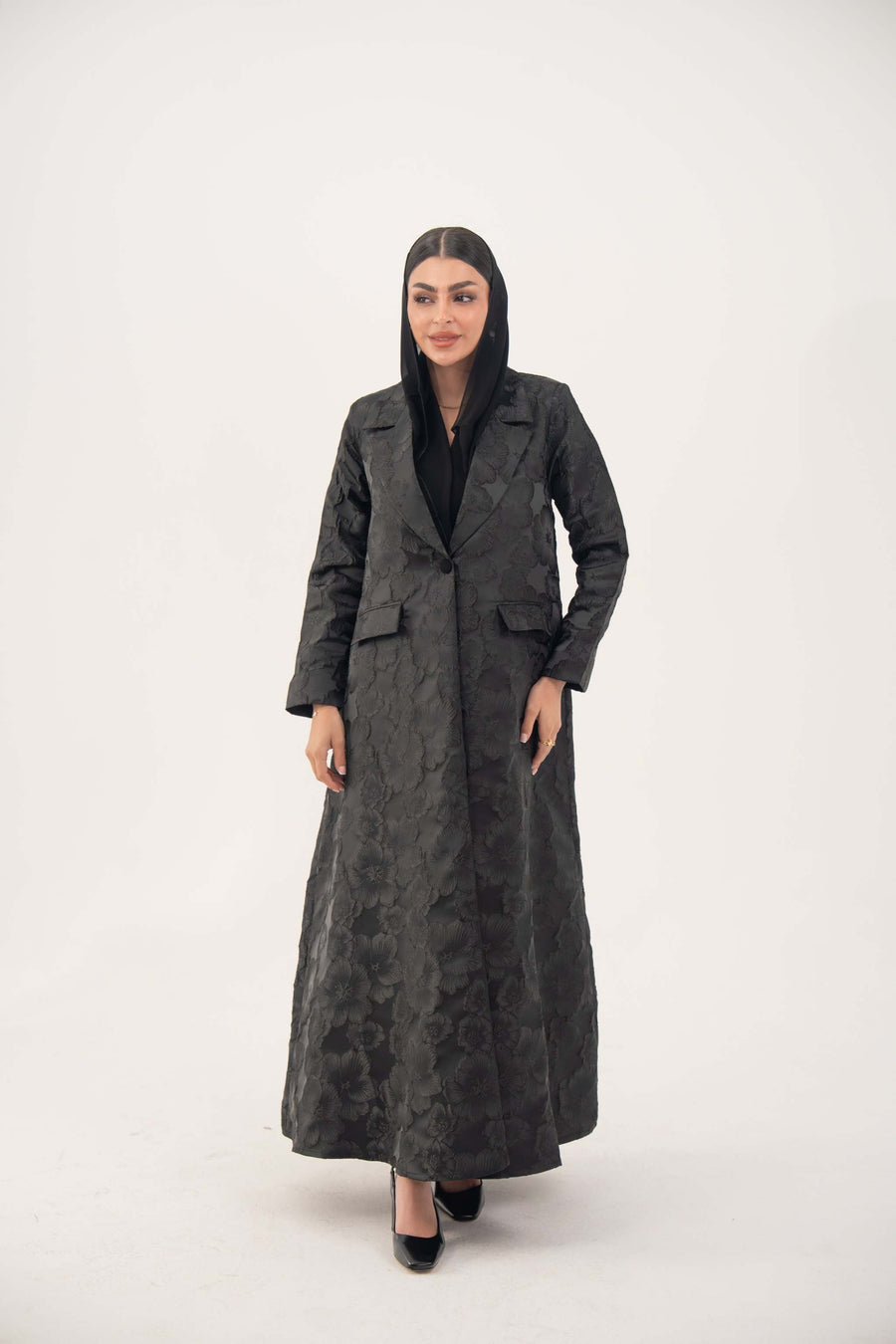 woman wearing a black jacquard blazer abaya with textured pattern and classic lapels