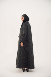 woman wearing black jacquard blazer abaya with textured pattern and classic lapels standing sideways