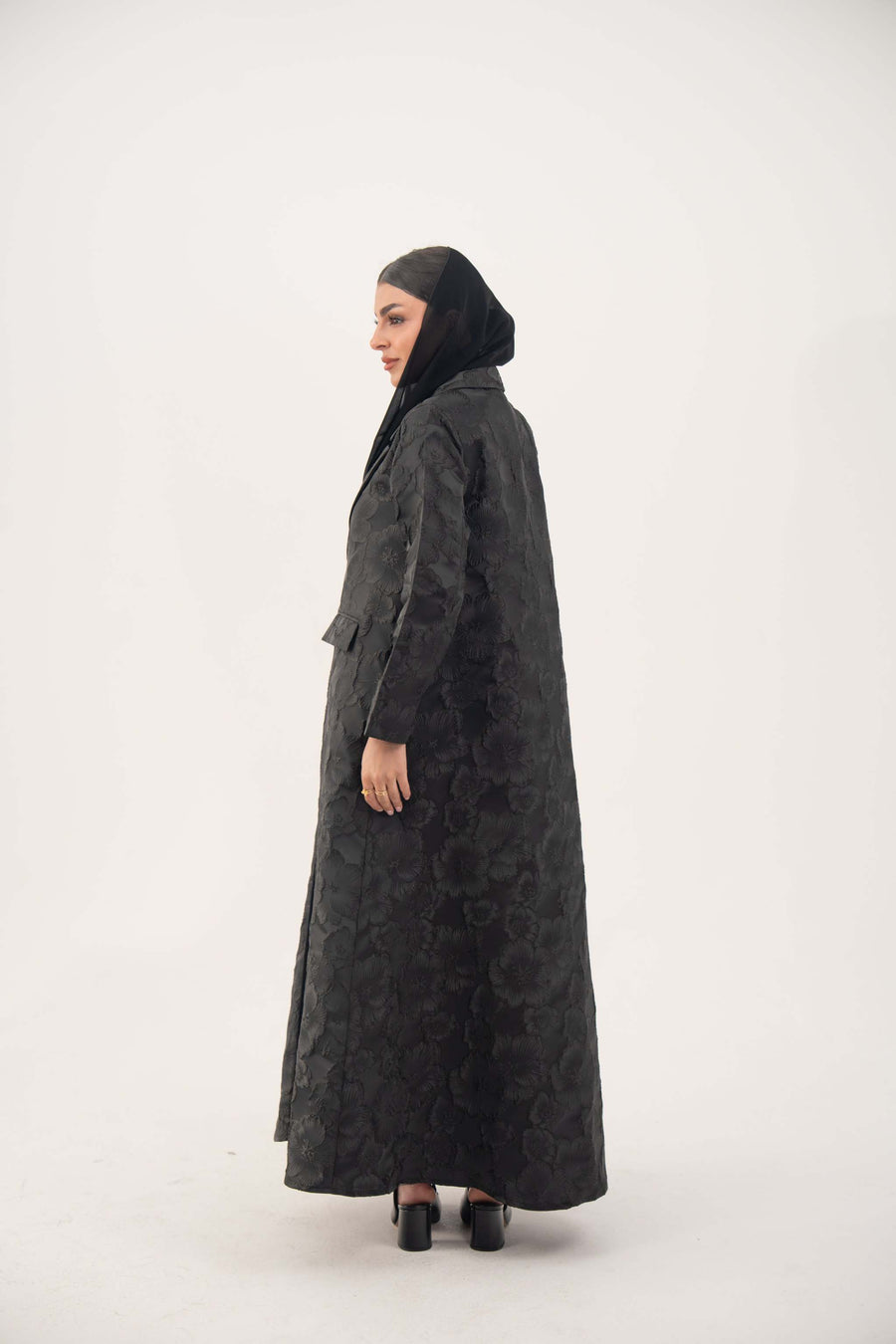 woman wearing black jacquard blazer abaya with textured pattern and classic lapels standing sideways