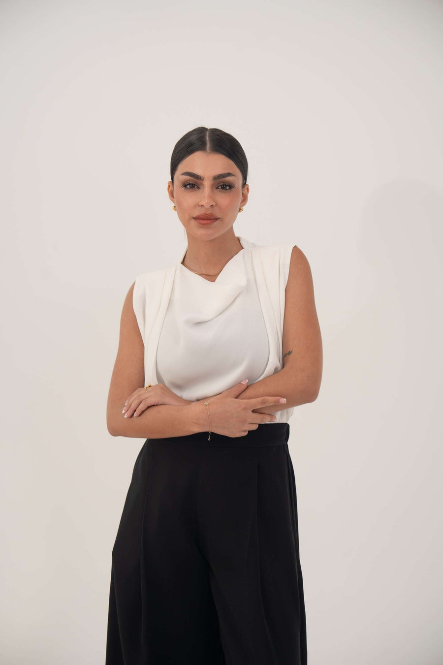 Woman wearing classic black wide-leg crepe pants with soft front pleats and elastic back, paired with a white sleeveless top.