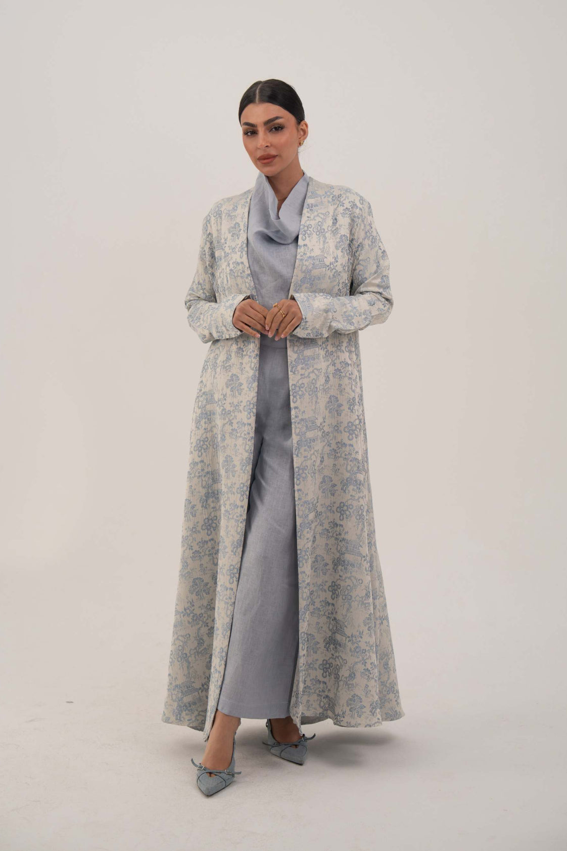 Woman wearing a soft jacquard silk patterned Hakaya open-front abaya with long relaxed cut and simple lapel, styled elegantly for comfort and sophistication