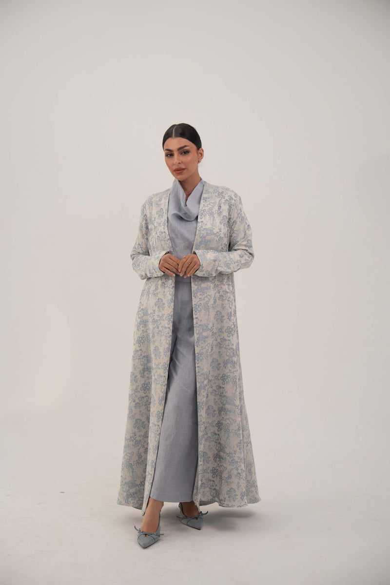 Woman wearing a soft jacquard silk patterned Hakaya open-front abaya with long relaxed cut and simple lapel, styled elegantly for comfort and sophistication