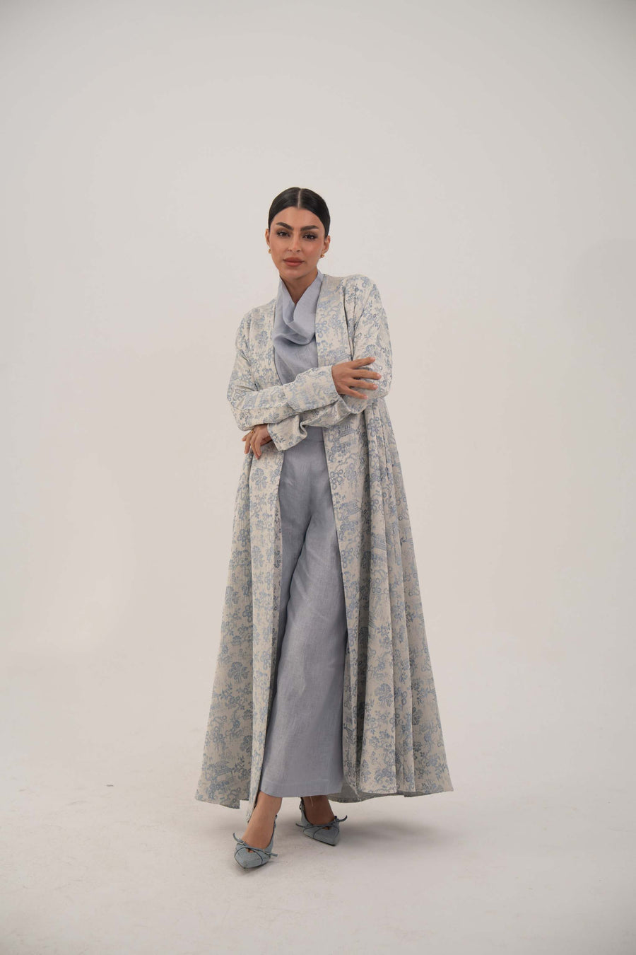 Woman wearing a long open-front jacquard silk abaya with a soft elegant pattern and simple lapel.