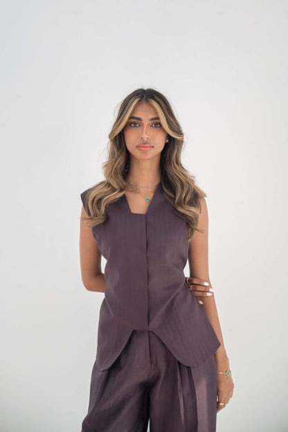 Woman wearing sleeveless ube vest made of high-quality twill linen blend with structured cut and hidden front buttons