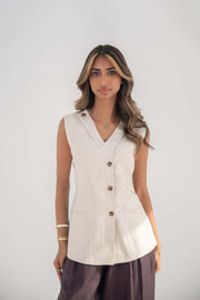 Beige sleeveless twill linen blend vest with V-neck, front buttons, side slits, and removable collar flap.